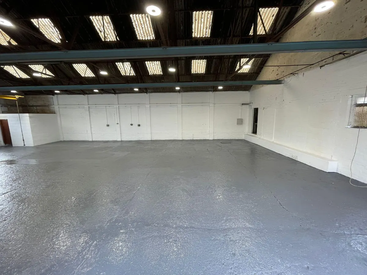 Completed industrial warehouse with freshly painted white walls and grey sealed floor coating