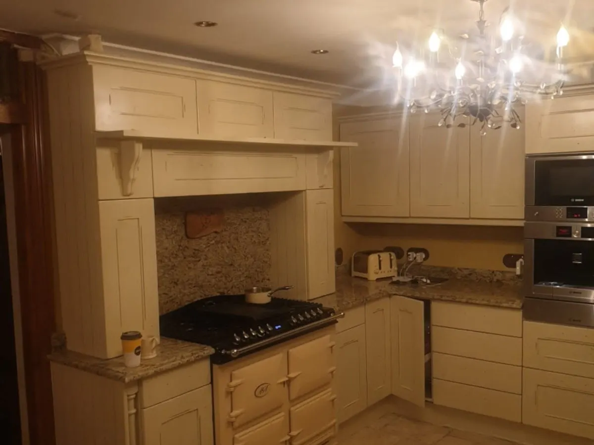 Traditional cream kitchen with sprayed cabinets range cooker granite worktops and chandelier