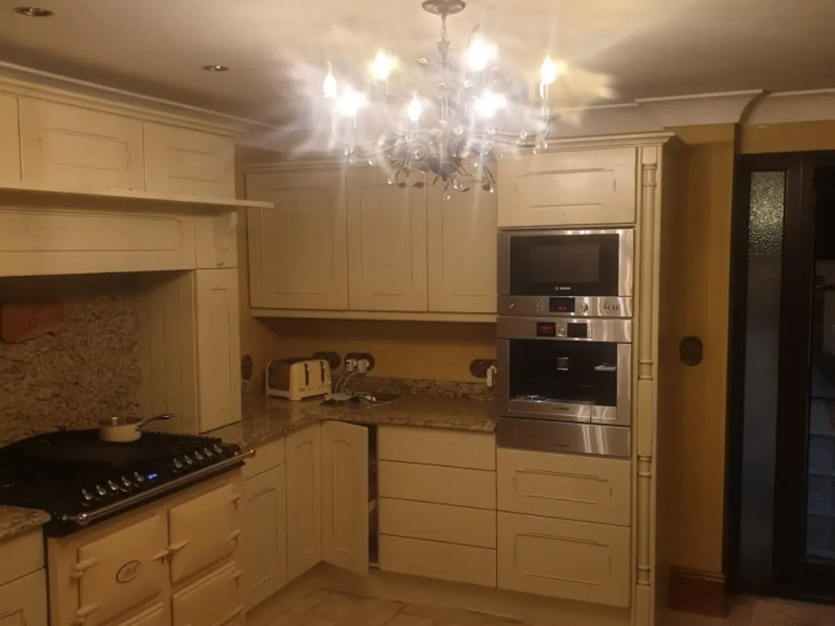 Traditional cream sprayed kitchen with Aga range cooker chandelier and granite worktops