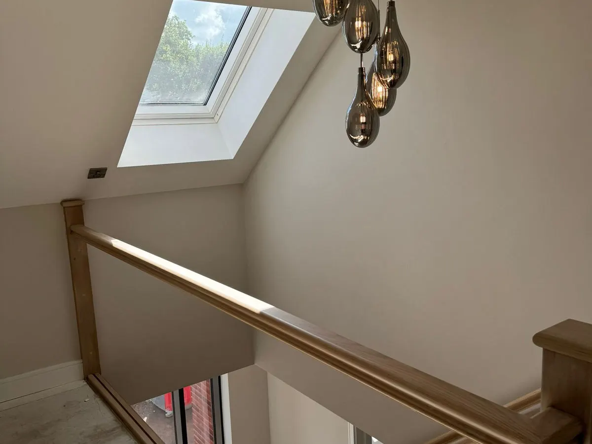Stairwell landing with freshly painted neutral walls oak banister and smoked glass pendant lights