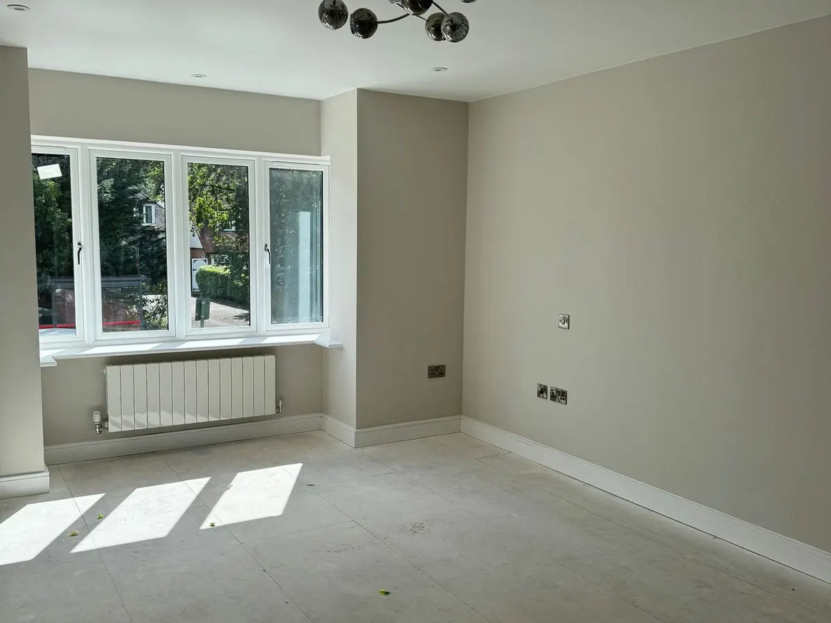 Freshly painted neutral room with bay window radiator and modern globe chandelier light fitting