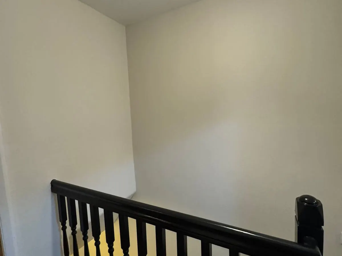 Freshly painted stairwell with clean cream walls and dark stained banister spindles
