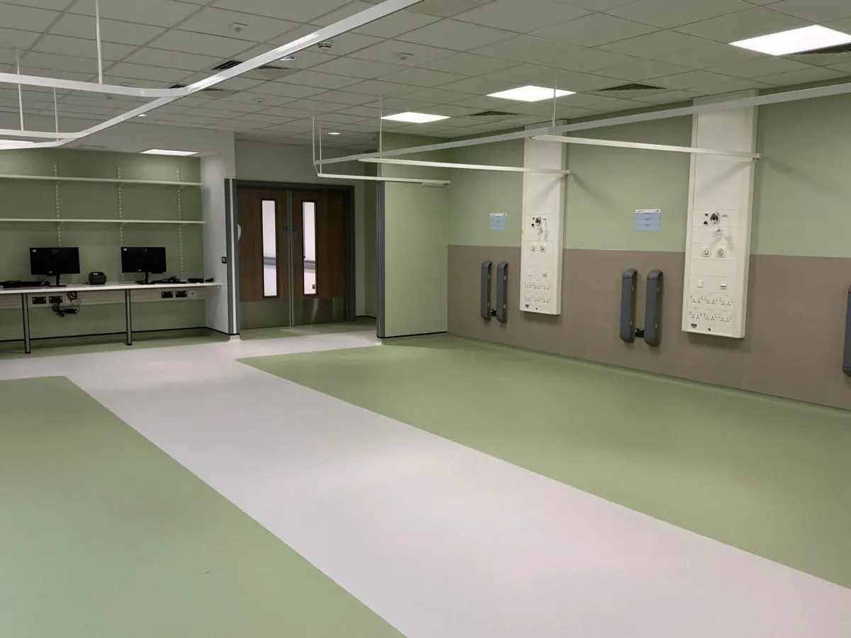 Hospital treatment room freshly painted in calming green with medical gas outlets and ceiling tiles