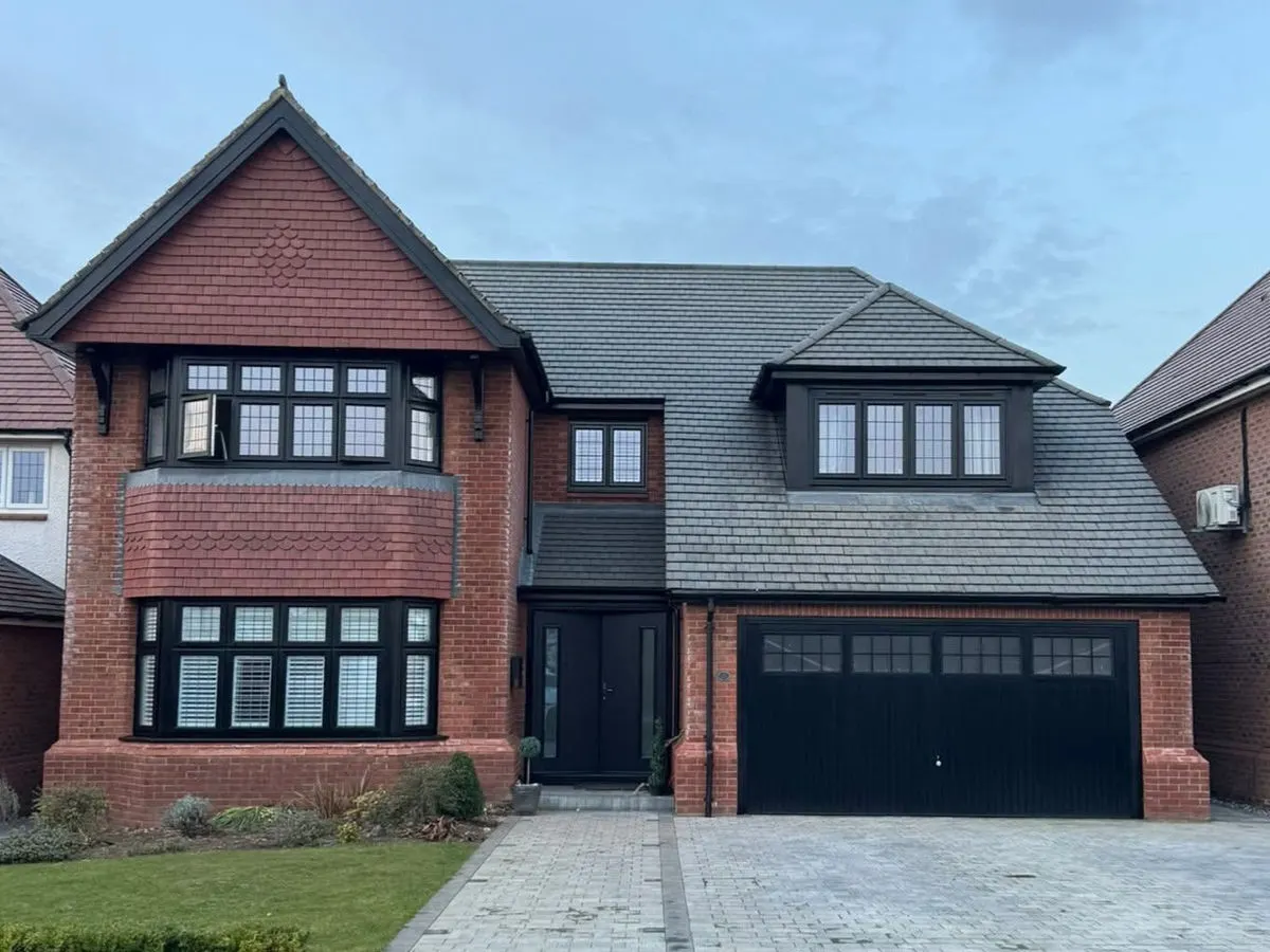 Detached brick house with anthracite black sprayed UPVC windows doors and matching garage door