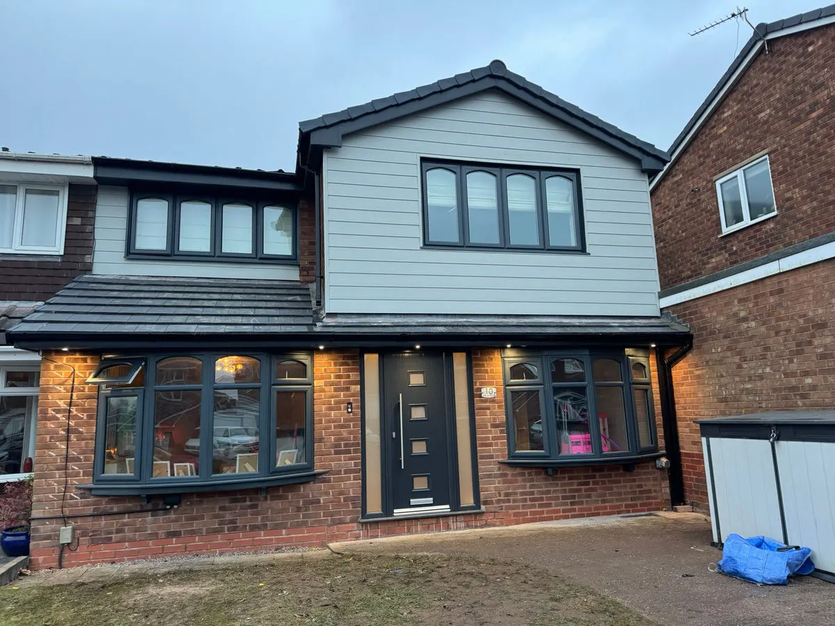 Detached house front with grey sprayed UPVC bay windows cladding and modern composite front door