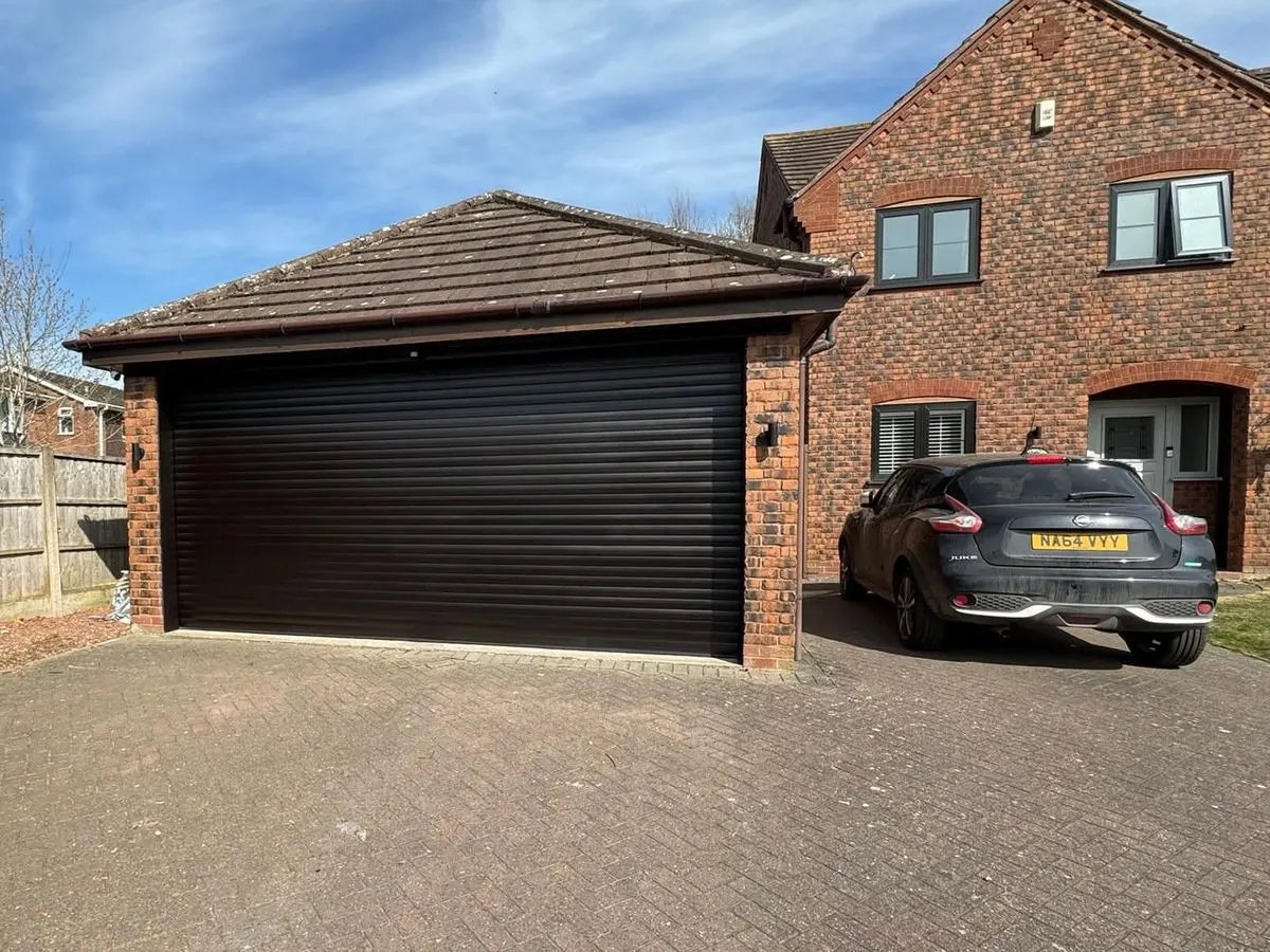 Brick house with dark brown sprayed roller garage door matching the UPVC window frames